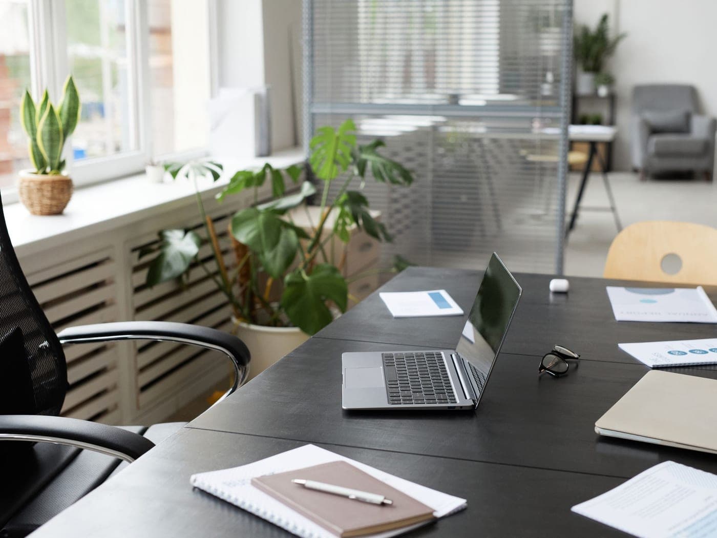 Poste de travail en bois clair près d'une fenêtre, plantes vertes et chaise de bureau