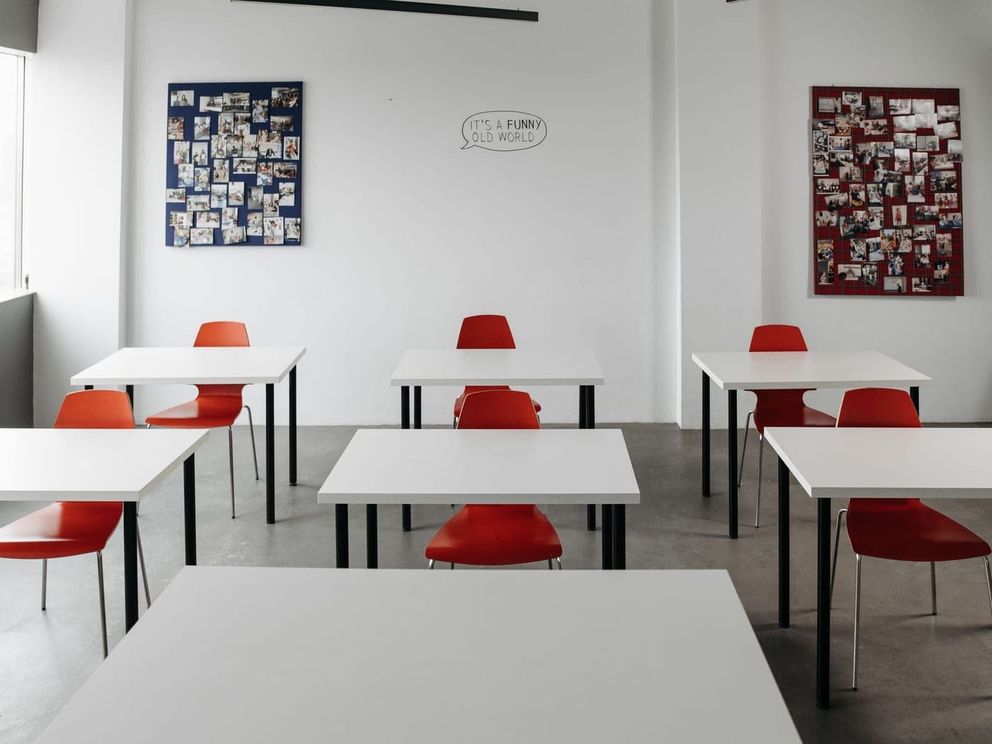 Salle de classe claire aux tables blanches et chaises rouges alignées