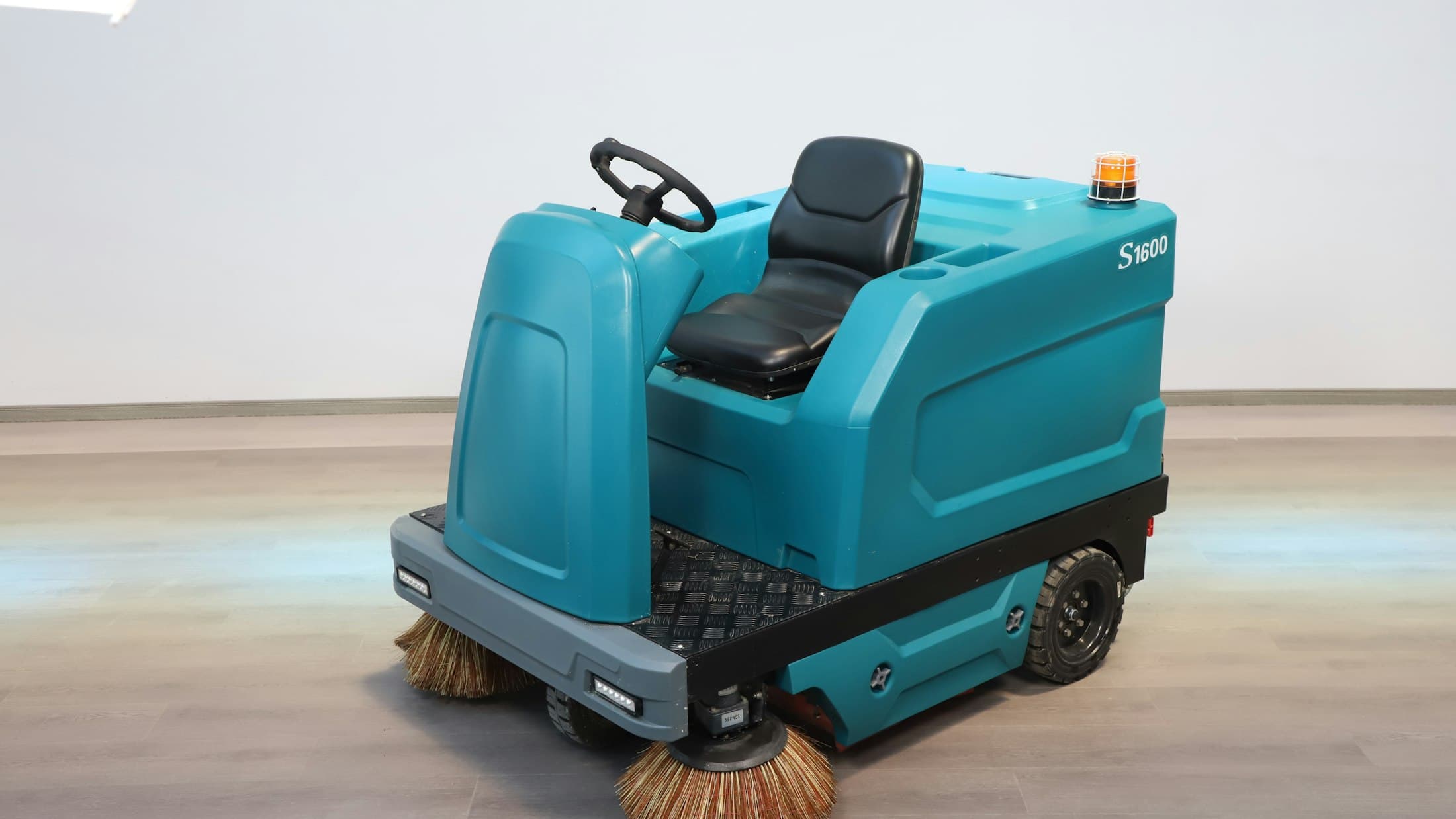 Autolaveuse autoportée turquoise posée sur un sol clair
