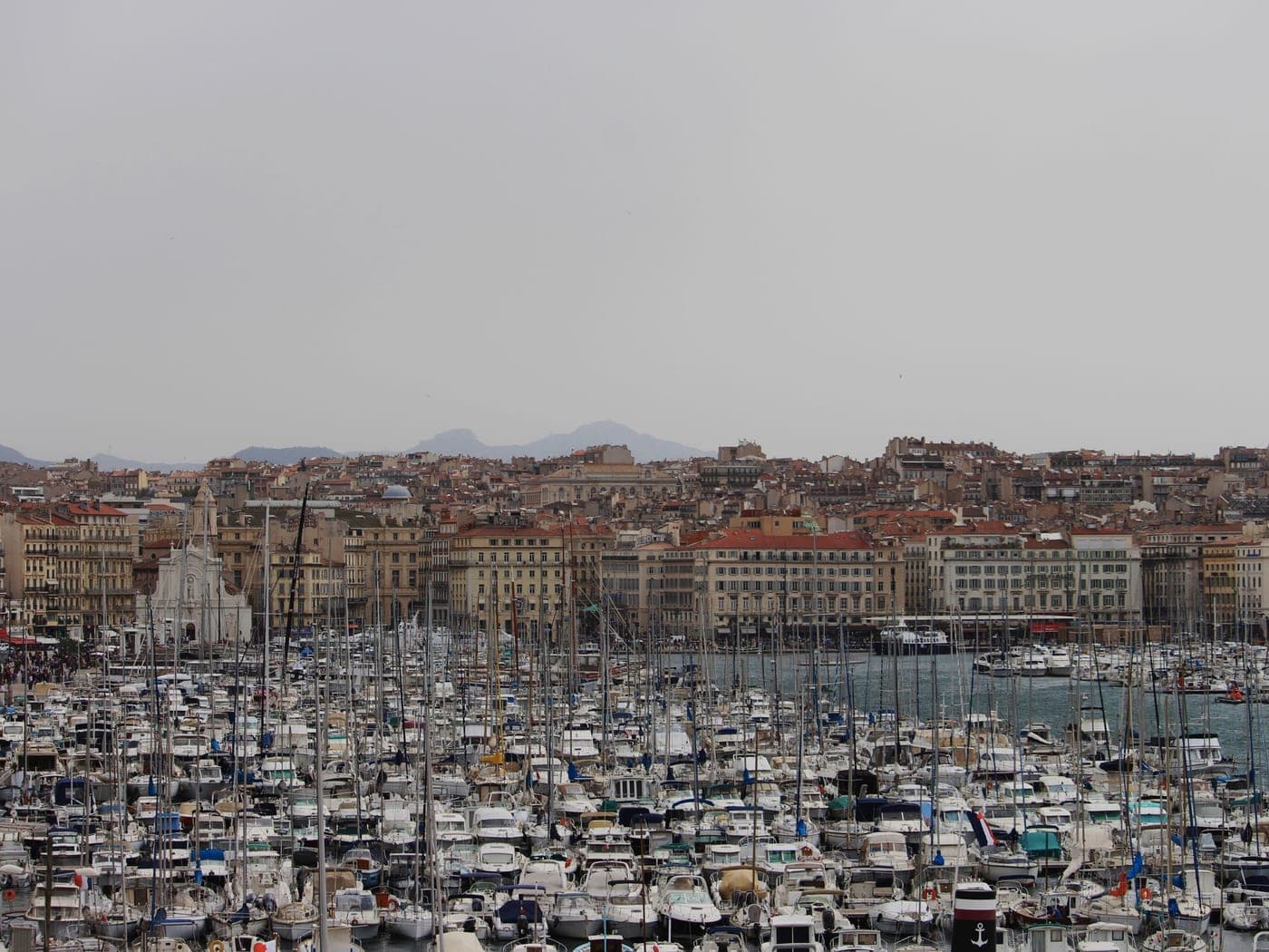 Vieux-Port de Marseille sous un ciel voilé, bateaux amarrés devant les façades de la ville