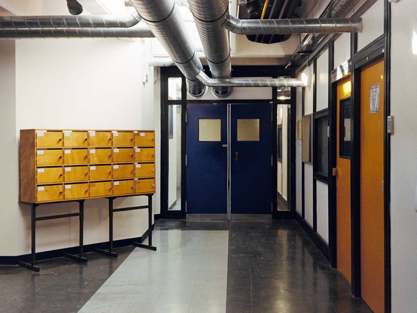 Hall d'immeuble avec boîtes aux lettres jaunes, couloir et portes bleues